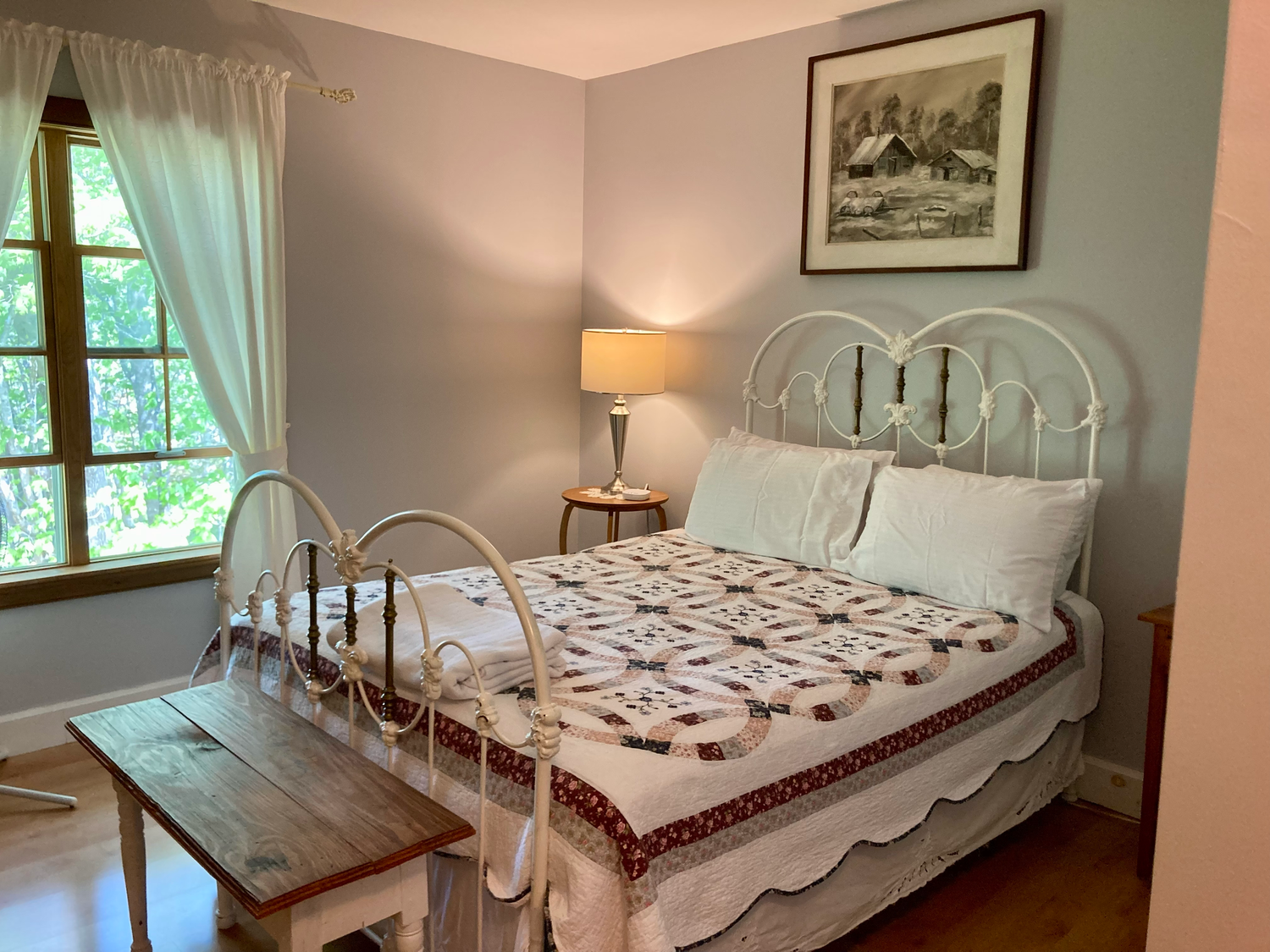 Guest room with a white iron bed and handmade quilt