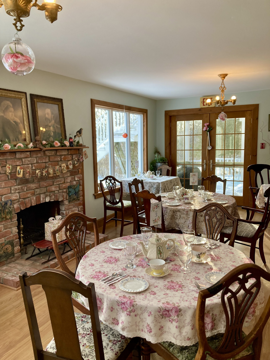 The parlour at Balsam Parlour with a fireplace, chandelier and set tables